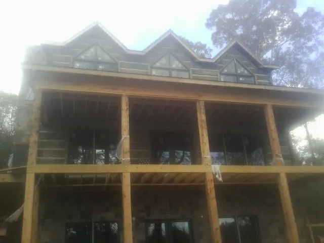 Dormers and porch framing on a large log home under construction — Roof Coating work by our crew in Clear Lake